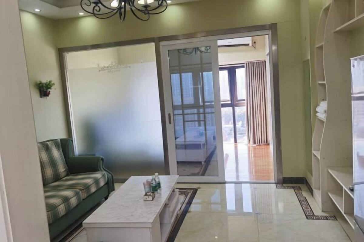 A living room with a sofa, a coffee table, and a sliding glass door leading to a balcony.