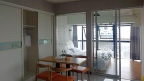 A hotel room with a bed, a table with chairs, a sliding glass door to the balcony, and a closet with a hanging rack. - Chuzhou Aidi Daily and Short-Term Rental Luxury Apartment (Chuzhou)