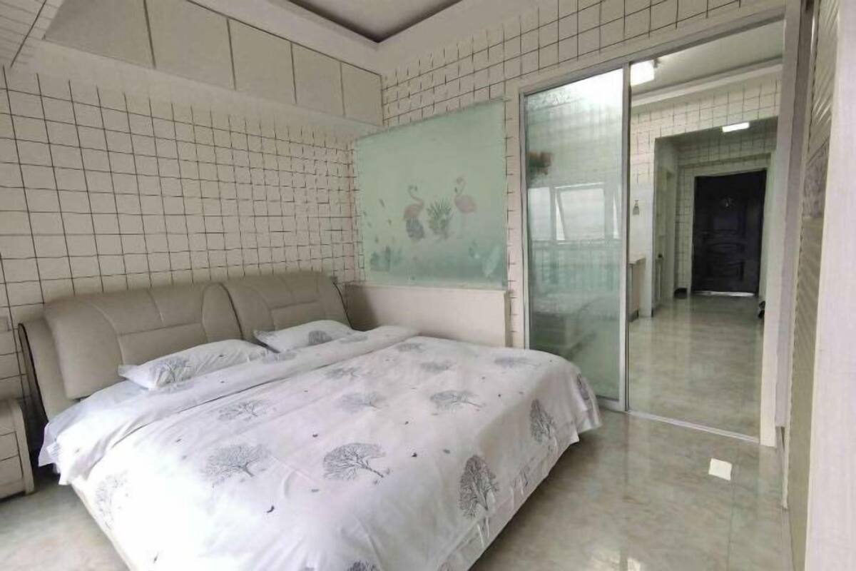A bedroom with a bed, a sliding glass door, and a tiled wall.