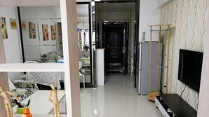 A modern hotel room with a large TV, a wardrobe, a desk with a chair, and a bed with a patterned bedspread. - Chuzhou Aidi Daily and Short-Term Rental Luxury Apartment (Chuzhou)