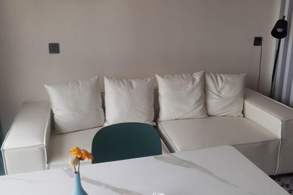 A modern living room with a beige sofa, a teal chair, and a white coffee table. - Chuzhou Aidi Daily and Short-Term Rental Luxury Apartment (Chuzhou)