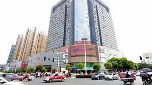 A high-rise building with multiple floors, a large commercial space with signage, and a busy street with vehicles and pedestrians. - Chuzhou Aidi Daily and Short-Term Rental Luxury Apartment (Chuzhou)