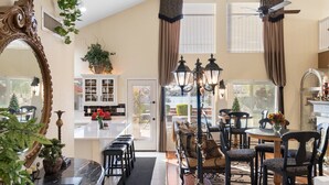 A spacious dining area with a high ceiling, a chandelier, and a large mirror. - Beautiful sunset Lakehouse with with amazing views and heated pool and jacuzzi ! (Avondale)