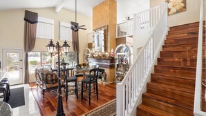 A spacious living area with a dining table, chairs, and a staircase with wooden steps. - Beautiful sunset Lakehouse with with amazing views and heated pool and jacuzzi ! (Avondale)