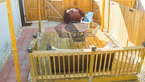 A wooden deck with a barbecue grill, outdoor table and chairs, and a covered seating area.