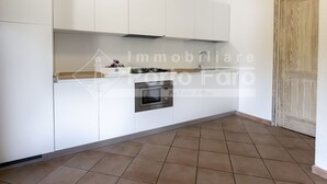 Een moderne keuken met witte kasten, een gasfornuis, een magnetron en een spoelbak.