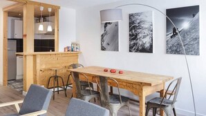 Eine moderne Küche mit Holzschränken und einem Essbereich mit Holztisch und Metallstühlen.