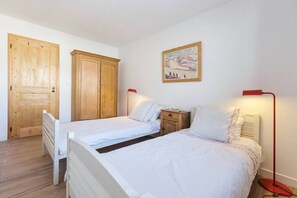 Camera da letto con due letti, armadi in legno, un quadro e lampade sui comodini.