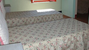A bedroom with two beds, a window with red shutters, and a view of a green landscape. - Apartment With Beautiful View in the Crete Senesi (Asciano)