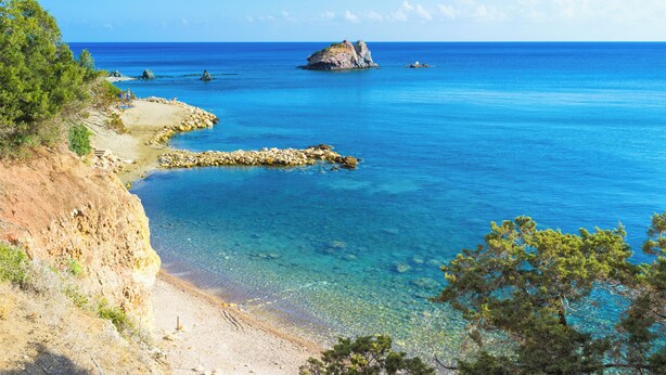 Un paysage côtier caractérisé par des eaux d’un bleu limpide, des rivages rocheux et une végétation clairsemée.