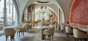A restaurant with high arched ceilings, modern furniture, and a view of the outdoors. - Five Palm Jumeirah - 2 Bdr - Hotel Facilities Incl (Dubai)