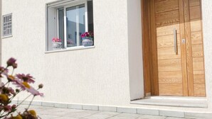 A building with a white exterior, a wooden door, and a window with a flower box.
