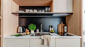 A modern kitchen with white cabinets, a black backsplash, and wooden shelves. - Sanders Port - Smart Studio Near Piraeus Port (Piraeus)