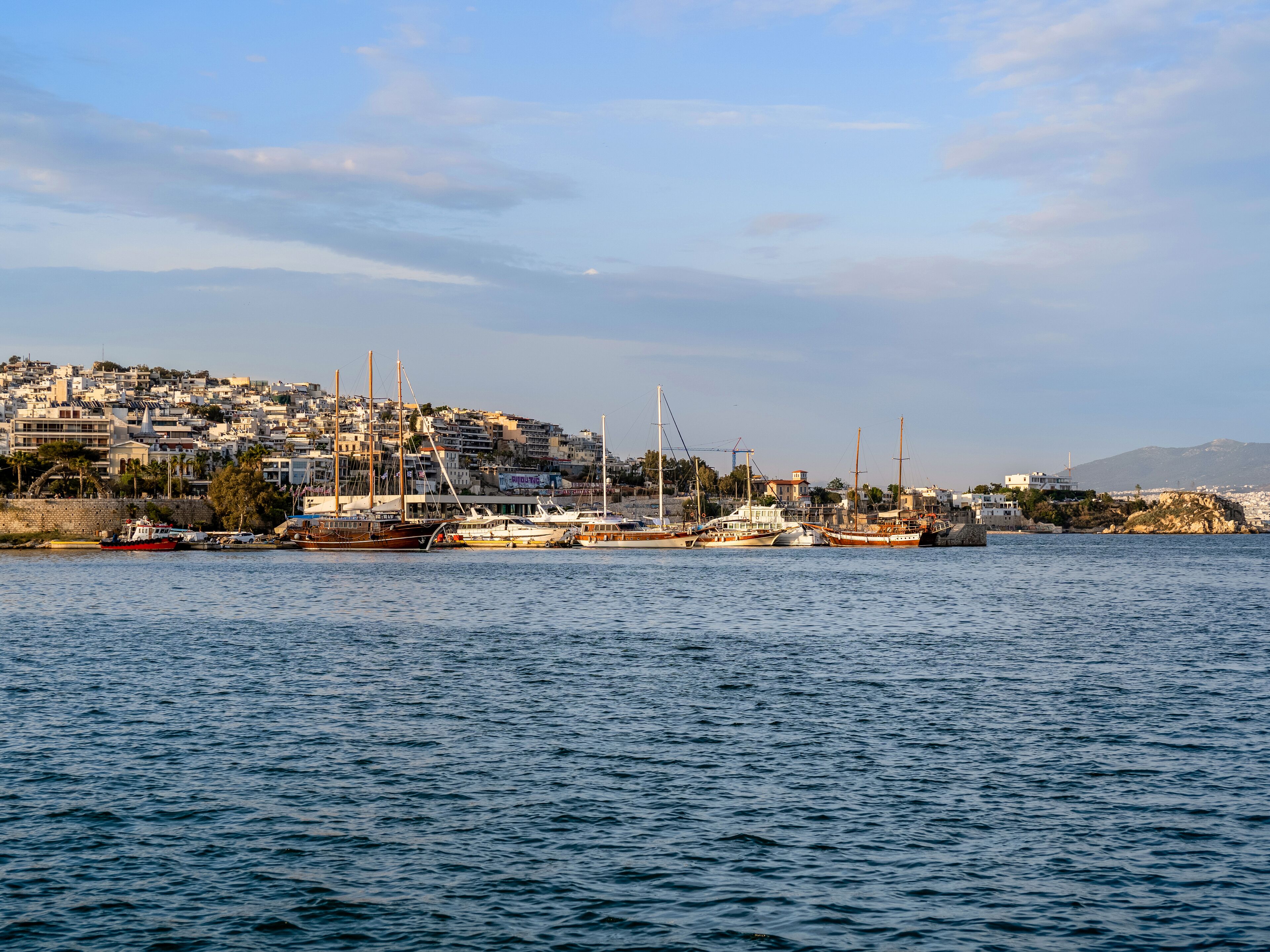 Un port avec des bateaux amarrés, une vue sur la ville en arrière-plan et un ciel dégagé.