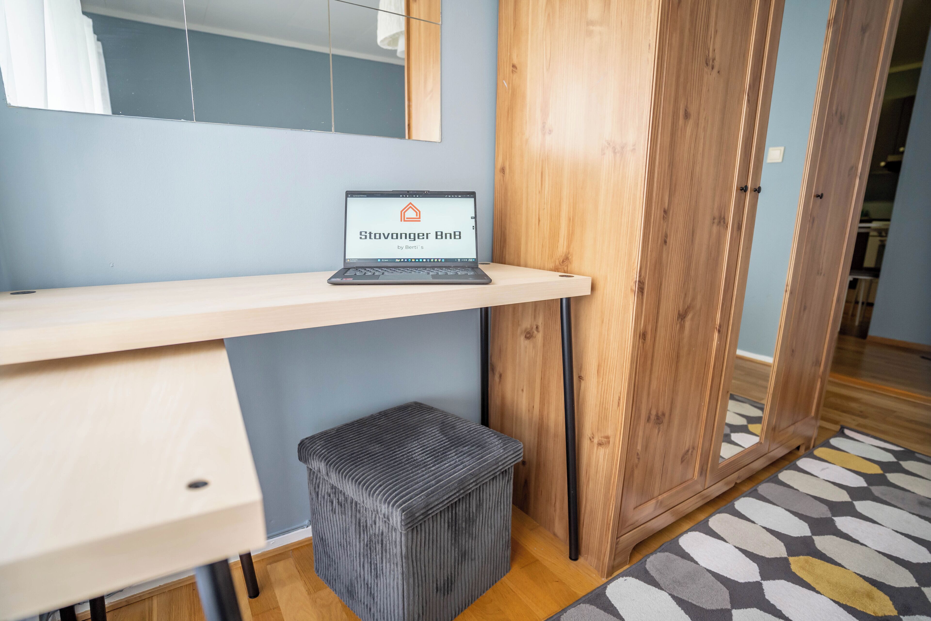 A laptop on a shelf with a wooden cabinet in the background.