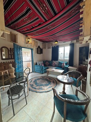 Una sala de estar acogedora con un sofá azul, una mesita de centro y un tapete estampado.