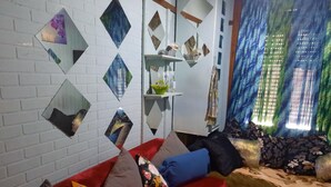 Ein Wohnzimmer mit einem roten Sofa, dekorativen Spiegeln und einem Fenster mit blauen Vorhängen.