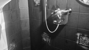 Ein Badezimmer mit Dusche, gefliesten Wänden und einem Spiegel.