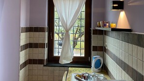 A compact kitchen with a window, a microwave, a kettle, and a small shelf with items. - Magnificent Villa Between Etna and the sea With Breathtaking Views of Mount Etna (Linguaglossa)