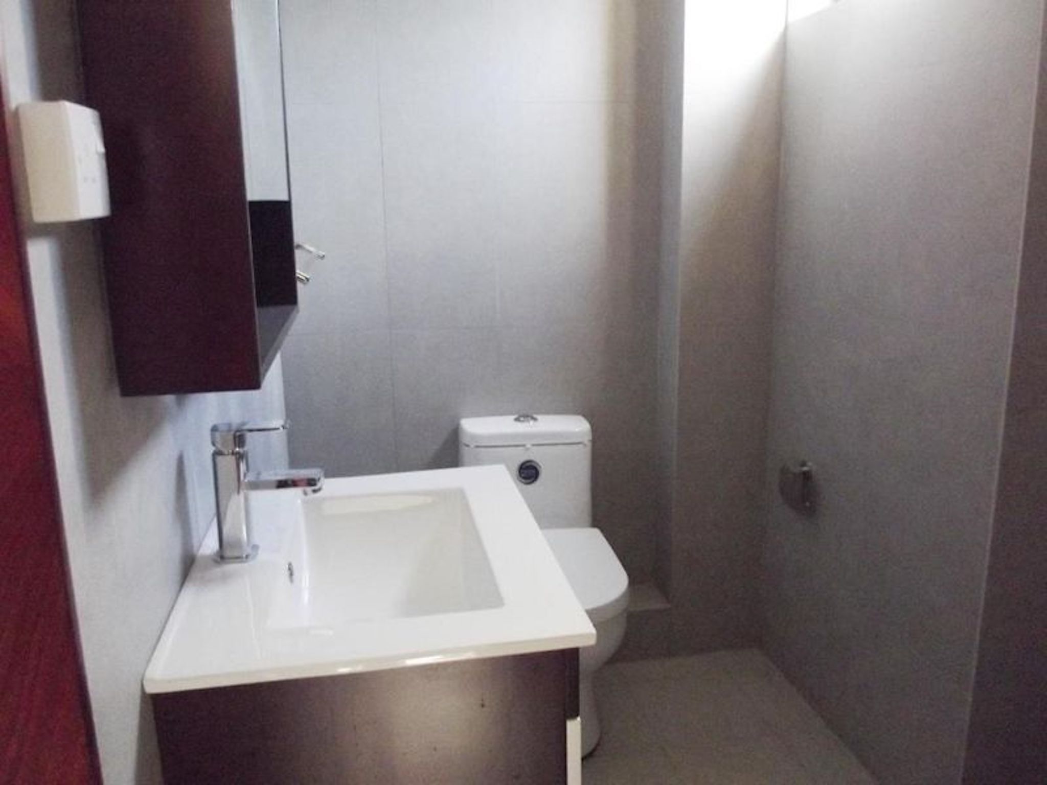 A small bathroom with a white sink, a mirror, and a toilet.