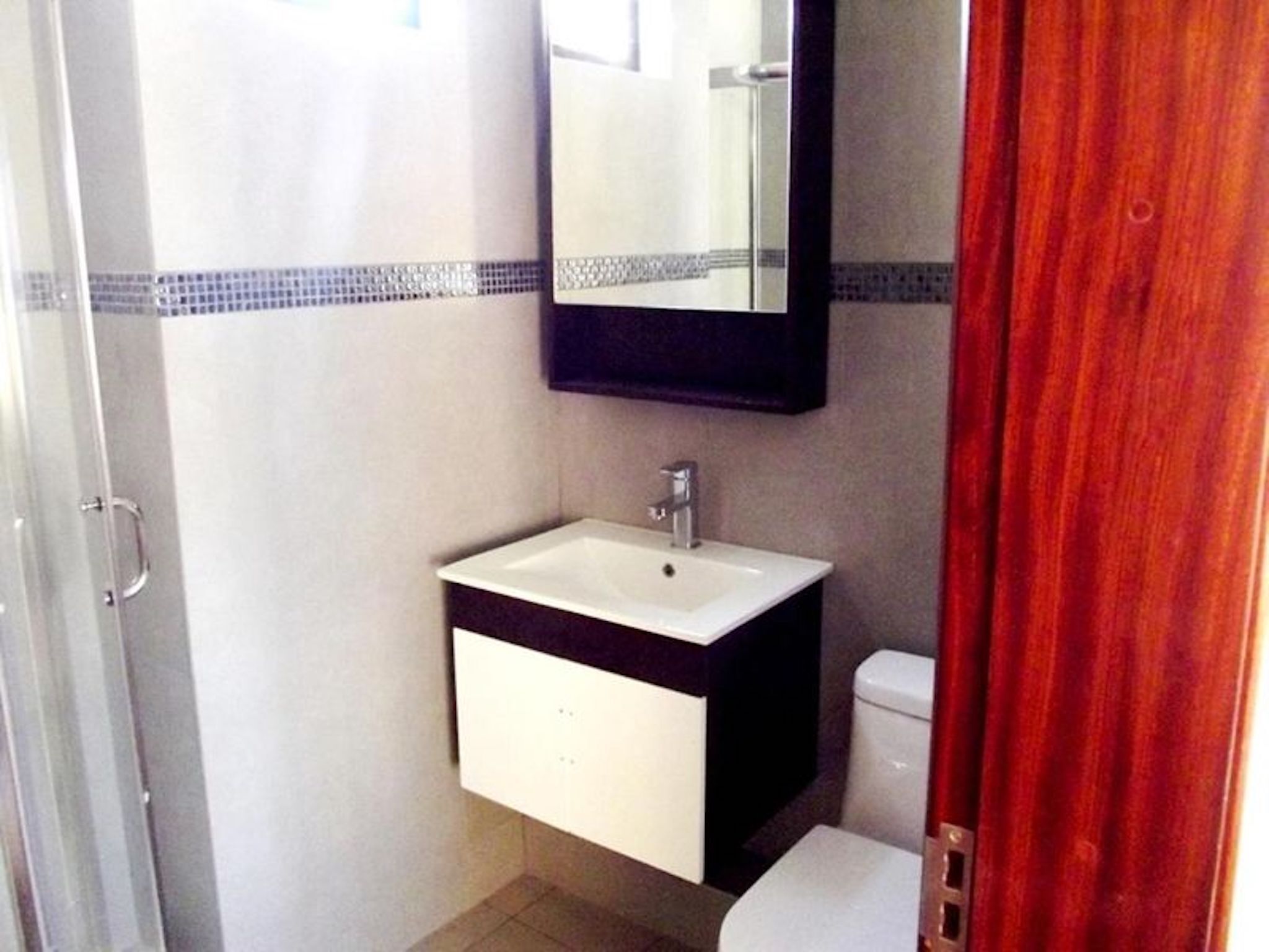 A bathroom with a white sink, a mirror above it, and a toilet.
