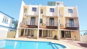 Un edificio de varios pisos con balcones y una piscina delantera.