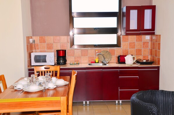Una cocina compacta con microondas, cafetera y hervidor en la encimera.