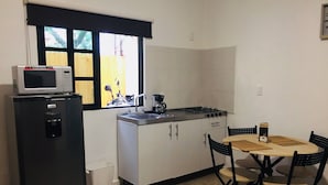 A compact kitchen with a refrigerator, stove, sink, and a dining area with chairs and a table. - Department, Studio Type Excellent Location (Mexico City)