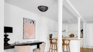 A modern kitchen with white cabinetry, a wooden island, and bar stools. There is a dining area with a round rug and two chairs. - City 1- Pleasant 4-bdr Apt in Central Copenhagen (Copenhagen)