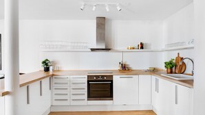 A modern kitchen with white cabinets, a wooden countertop, a built-in oven, and a stainless steel range hood. - City 1- Pleasant 4-bdr Apt in Central Copenhagen (Copenhagen)