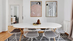 Un comedor con una mesa redonda, cuatro sillas y dos cuadros abstractos en la pared.