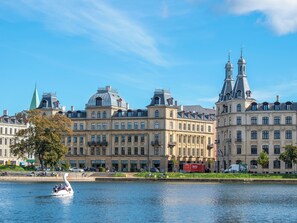 A historic building with classical architecture, a river in the foreground, and a swan-shaped boat. - Constantin - Chic 2-bdr Apt With Balcony (Frederiksberg)