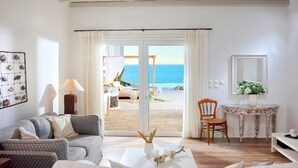 Una habitación con vistas al mar, un sofá, una silla, una mesa con un jarrón y un espejo.