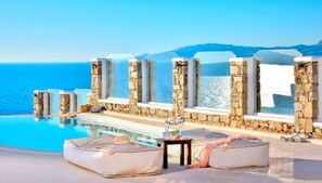 Un espace aménagé au bord de la piscine, avec des murs en pierre, une vue dégagée sur la mer et un fauteuil de relaxation.
