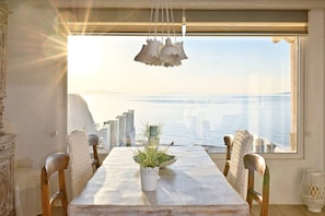 A dining area with a table, chairs, and a view of the sea.