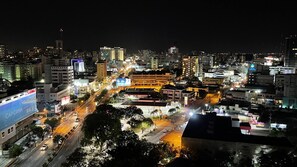 Un paisaje urbano nocturno con edificios iluminados y calles animadas.
