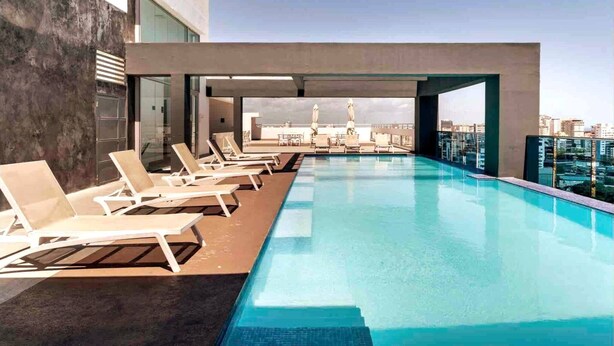 A rooftop infinity pool with lounge chairs, a clear view of the city skyline, and a modern architectural design. - Apartment N1001 Downtown Santo Domingo (Santo Domingo)