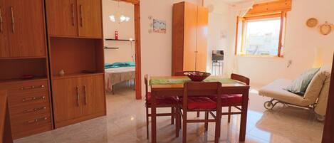 A compact living space with a dining area, kitchenette, and a small seating area with a sofa.