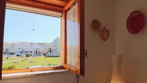 Une pièce dotée d’une grande fenêtre, d’une lampe fixée au mur et de deux paniers en osier.