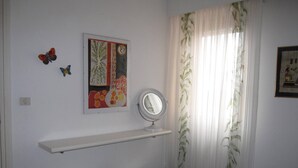 Une chambre à coucher comprenant un lit, deux tables de chevet, un miroir et une étagère murale ornée d’un tableau.