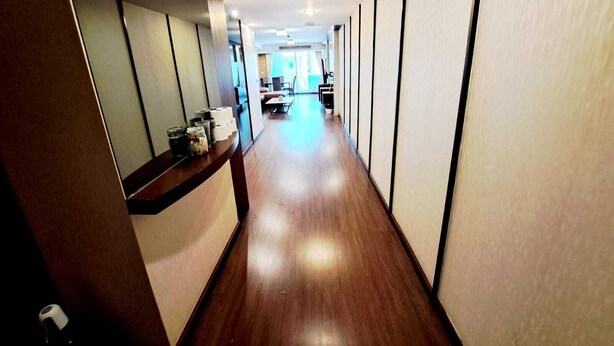 A hallway with wooden flooring and a reception desk with amenities. - 6C - 2 Bedroom Downtown Apartment With Shared Pool (Bangkok)