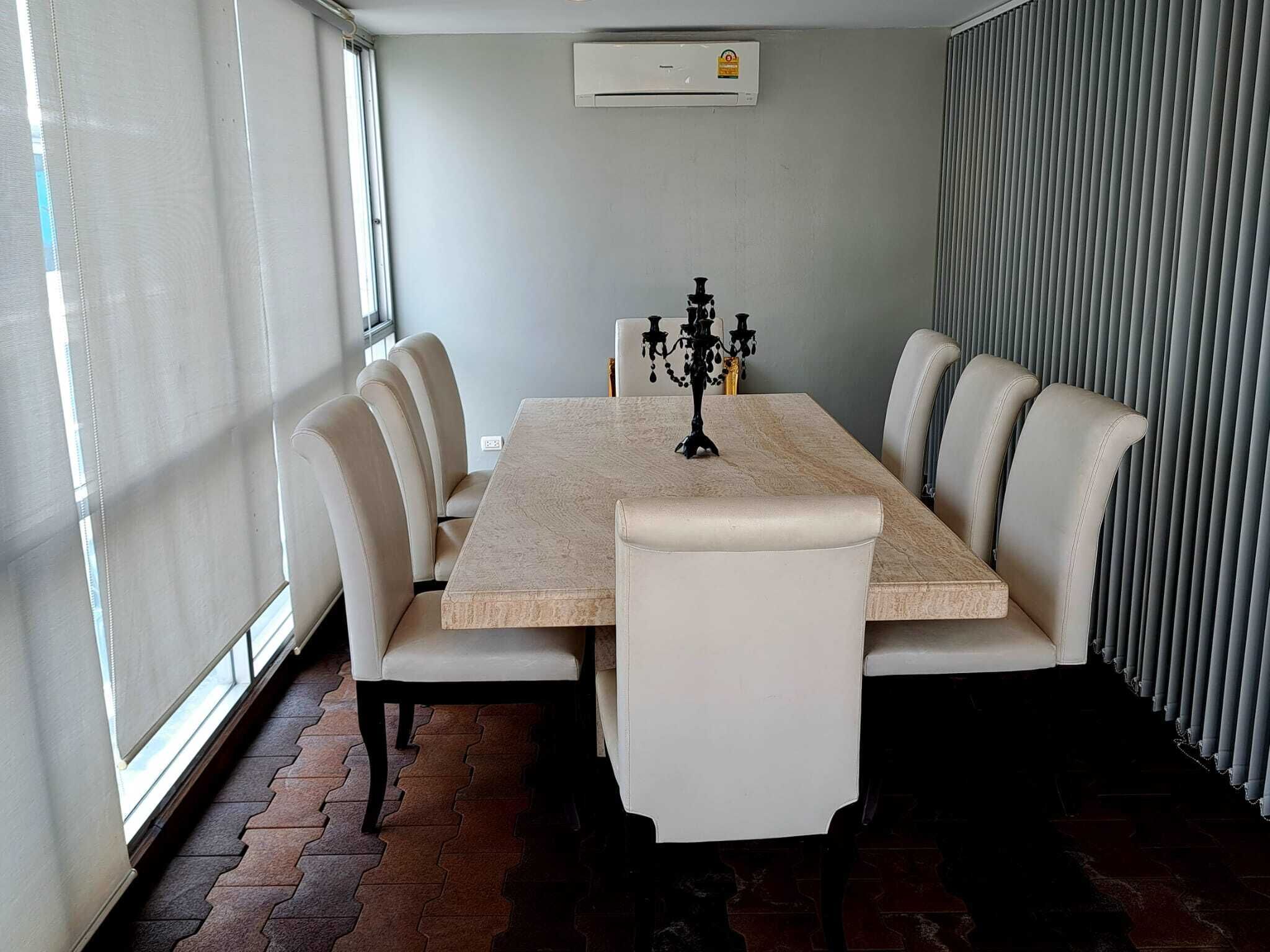 A dining area with a rectangular table, six chairs, and a black candelabra.