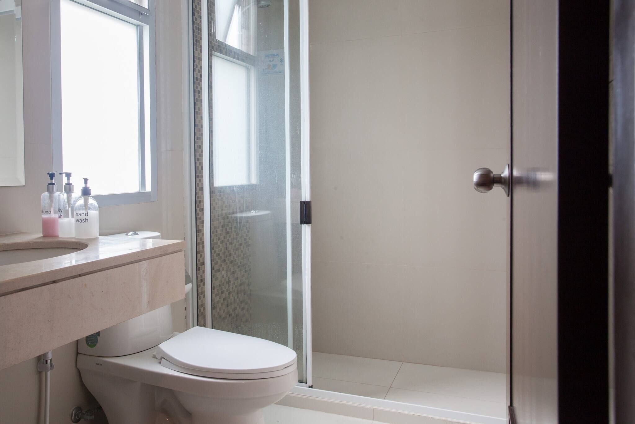 Un baño con inodoro, lavamanos y zona de ducha.