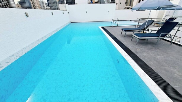 A rooftop swimming pool with clear blue water, surrounded by white walls and a few lounge chairs. - 7A - 2 Bedrooms and 2 Bathrooms Located at Downtown Apartment With Shared Pool (Bangkok)