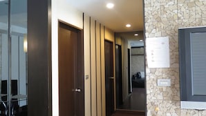A hallway with wooden doors, a stone wall, and a sign on the wall. - 7A - 2 Bedrooms and 2 Bathrooms Located at Downtown Apartment With Shared Pool (Bangkok)