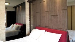 A hotel room with a large bed, a separate seating area, and a wooden panel wall. - 7A - 2 Bedrooms and 2 Bathrooms Located at Downtown Apartment With Shared Pool (Bangkok)