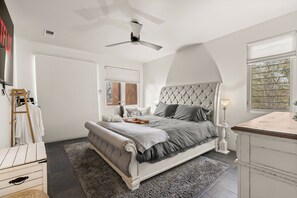Relax in this serene bedroom with a large bed, tufted headboard, and comfortable bedding.