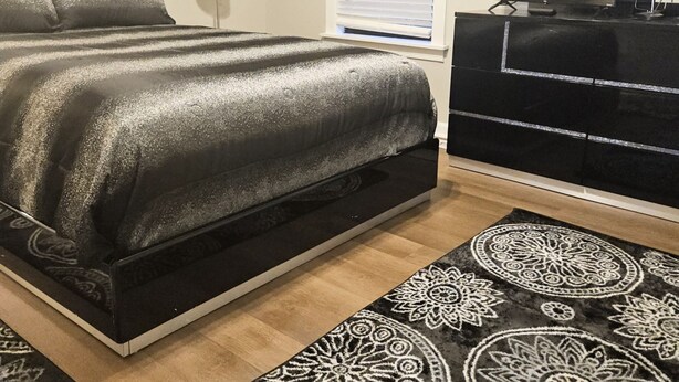 Een slaapkamer met een bed, een kaptafel, een televisie en kamerbreed tapijt met een patroon.