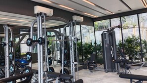 A modern gym with various exercise equipment, large windows, and a view of the outside. - B201 - 1 Bedroom Condo With Sea View, Ao Nang Beach (Krabi)