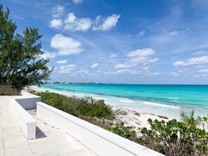 Une vue sur la côte, avec un ciel dégagé, une mer turquoise et un bâtiment blanc doté d’un balcon donnant sur la plage.
